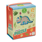 Illustrated puzzle box by Floss & Rock featuring a triceratops dinosaur in a prehistoric landscape with colorful dinosaur footprints, a fossilized ammonite, and a vibrant orange-and-white braided rope handle