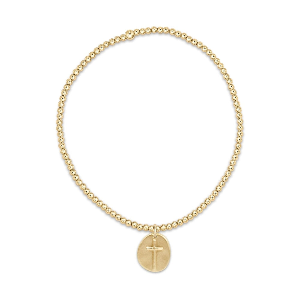 Gold beaded stretch bracelet with a round pendant featuring a cross