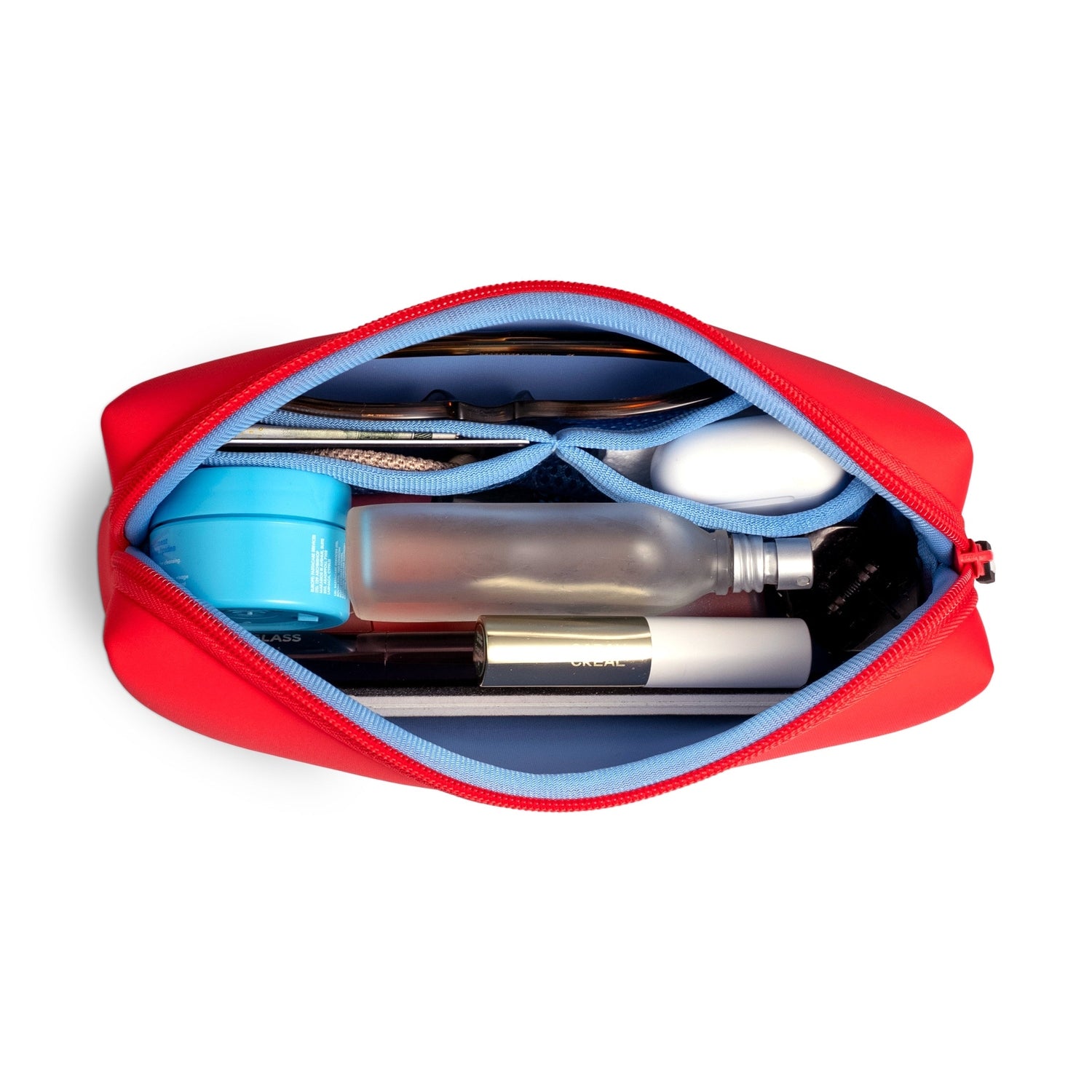 Open red zippered pouch containing various personal items including a blue jar and cosmetic bottles