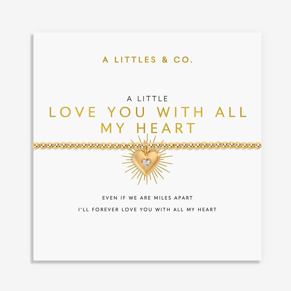Gold beaded bracelet with a sunburst heart charm on a display card with text