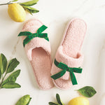 Pink slippers with green bows on a white background with lemons and leaves.