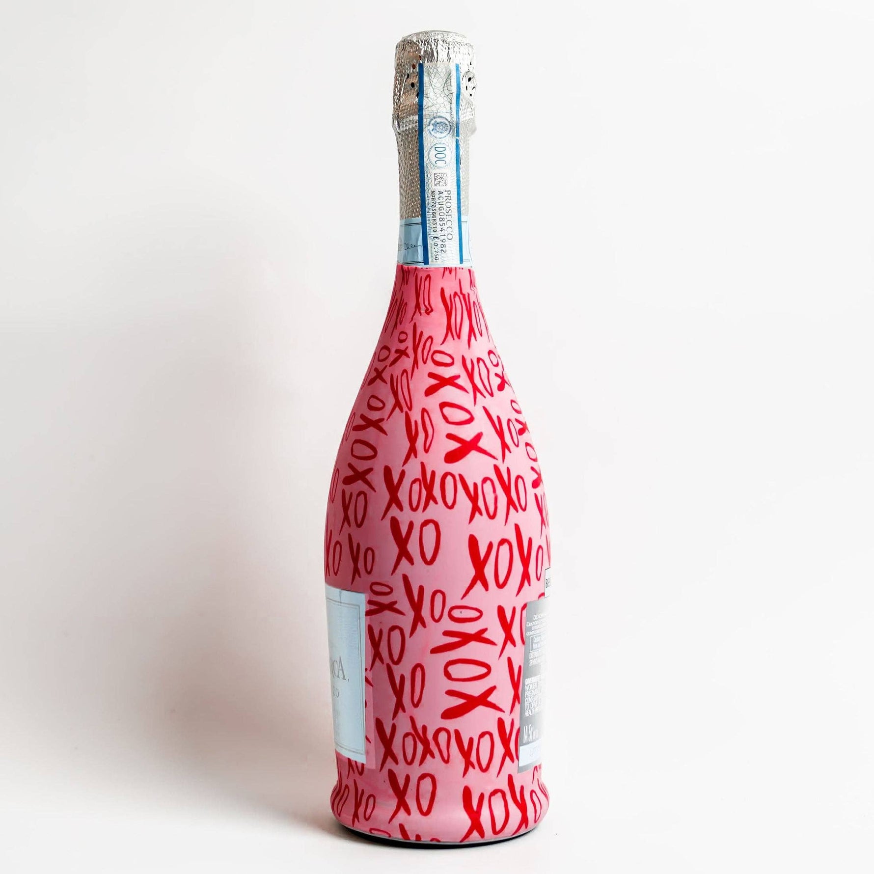 Bottle wrapped in red paper with 'XO' pattern on a white background
