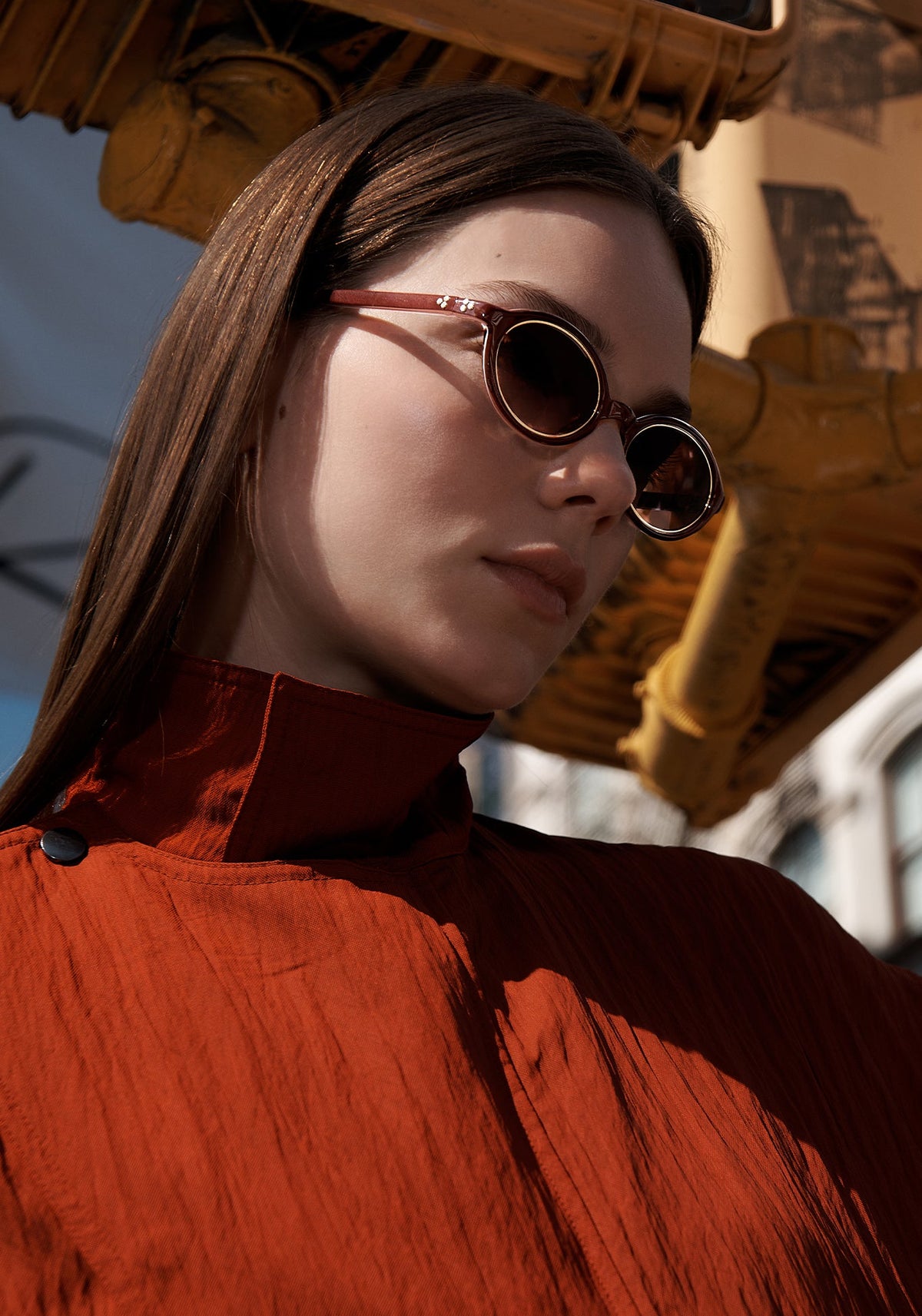 Woman in a rust top wearing oval brown sunglasses