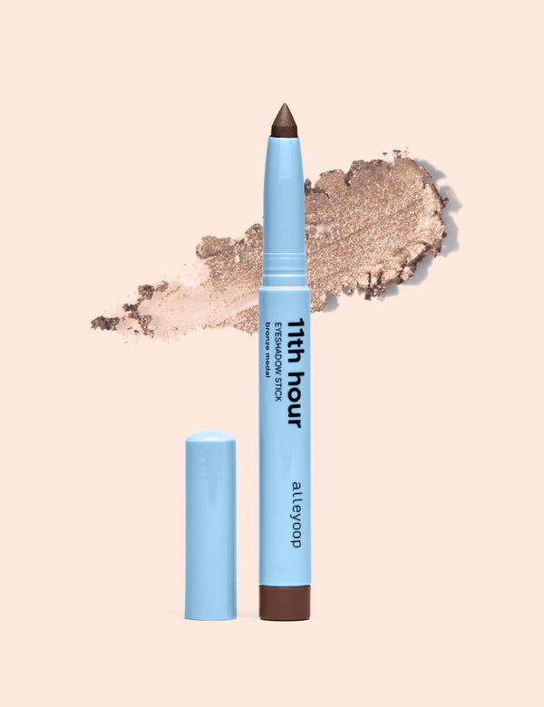 Bronze eyeshadow stick with cap removed and bronze swatch behind it
