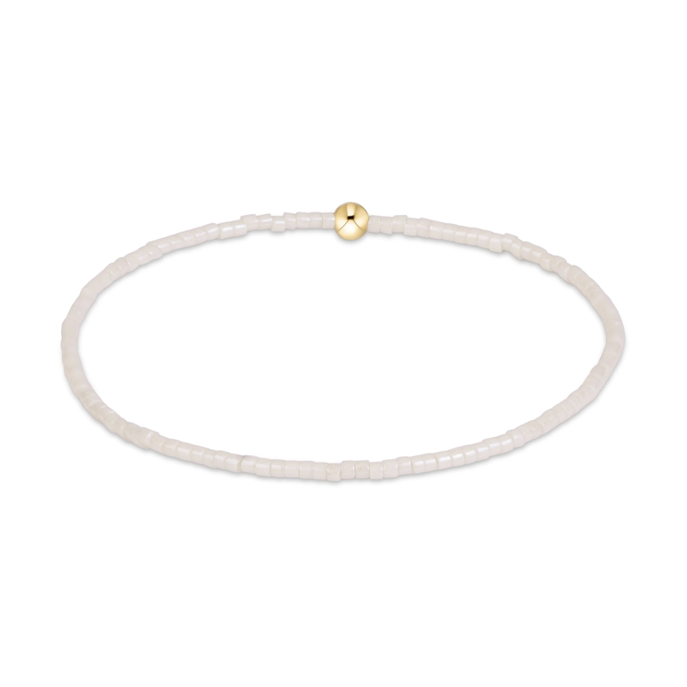 White seed bead stretch bracelet with a single gold bead