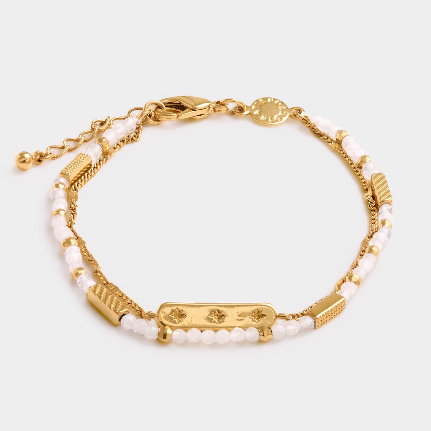 Gold double chain bracelet with white beads and a central rectangular charm featuring three engraved star symbols
