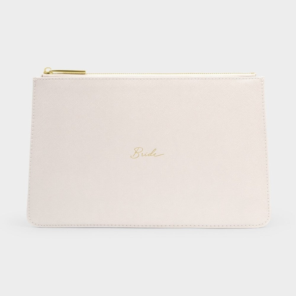 Studio photograph of a cream-colored saffiano leather bridal clutch centered on a neutral gray background featuring delicate gold cursive script reading Bride and a matching metallic zipper pull