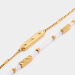 Gold chain bracelet with a rectangular bar charm and a second strand of white beads and gold accents