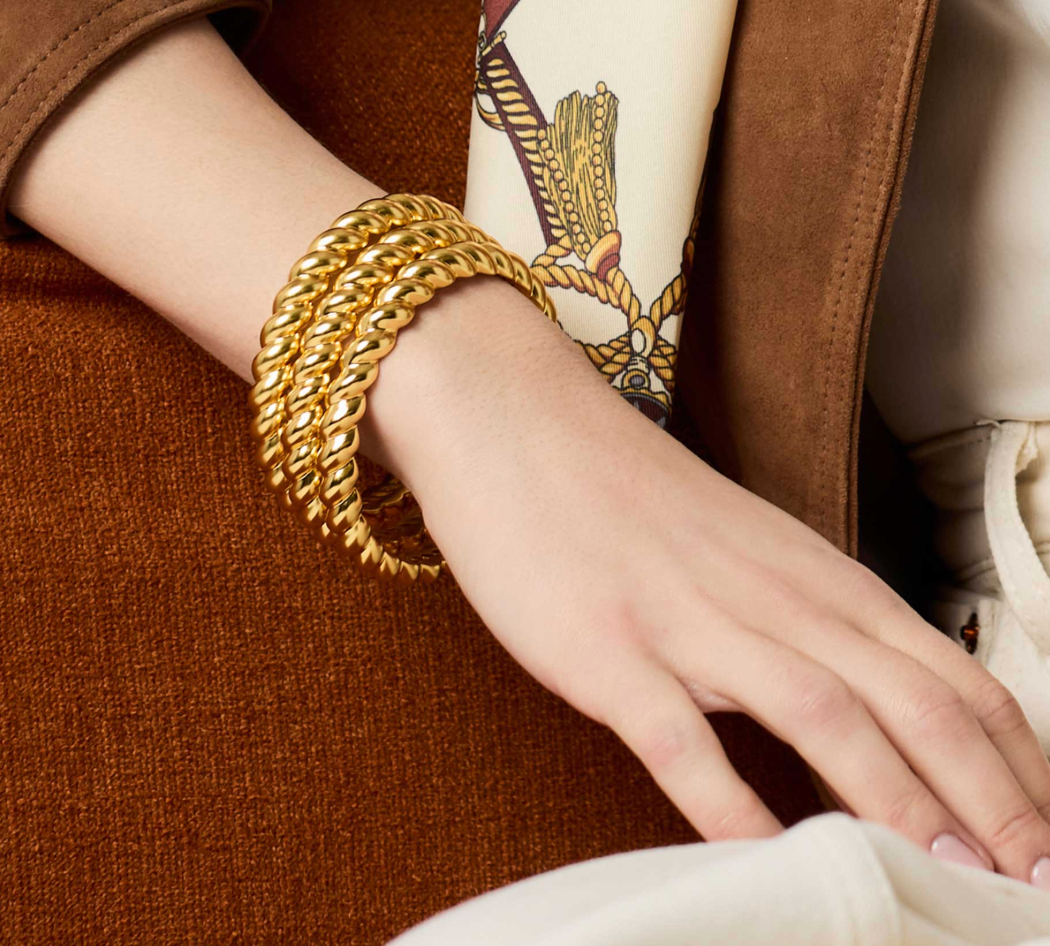 Gold twisted rope bangle worn on a wrist