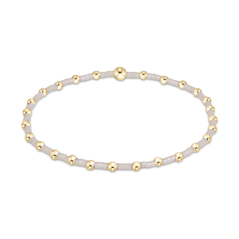White seed bead stretch bracelet with gold bead accents