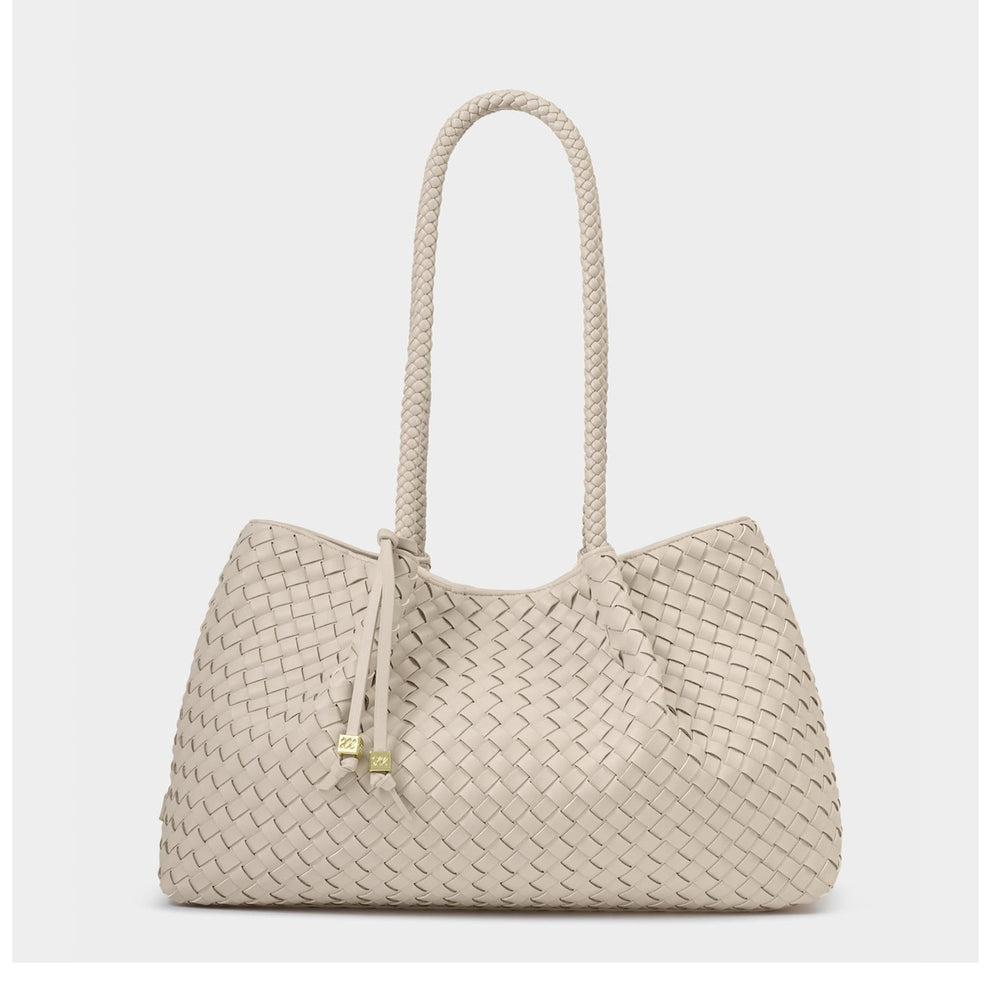 Handcrafted woven leather handbag featuring a cream Intrecciato pattern, a single long braided shoulder handle, and gold-toned cube charms on slender leather ties against a neutral studio background