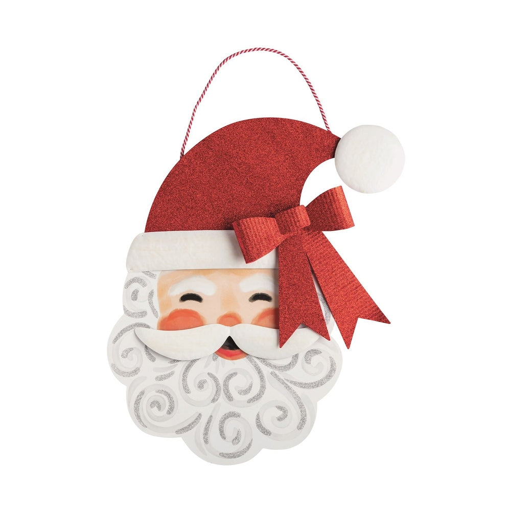 Painted metal wall hanging of a vintage-style Santa Claus head featuring a prominent red glittery bow, a white curly beard with silver glitter accents, and a red and white striped baker's twine for suspension