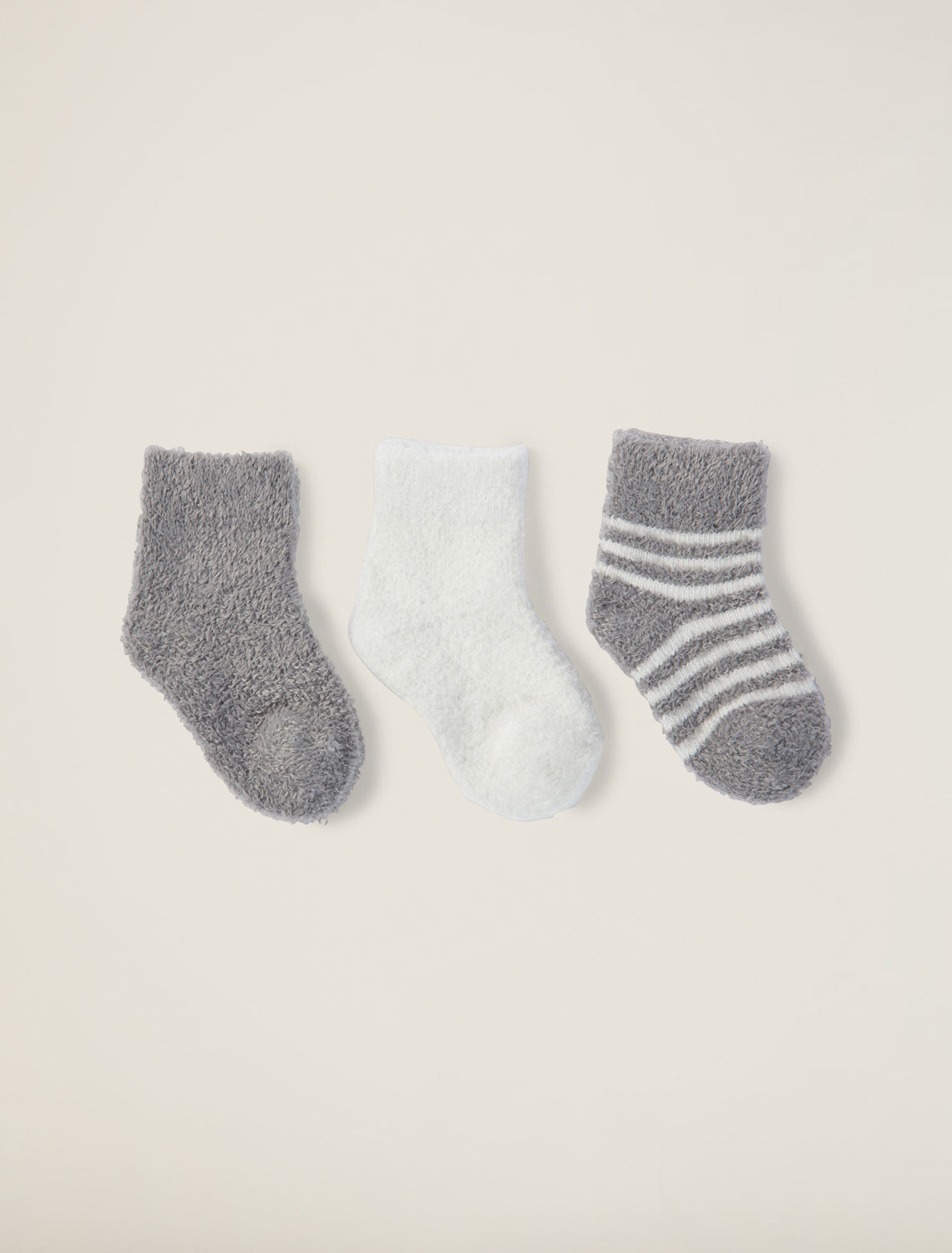 a white sock, grey sock, and white and grey striped sock on a taupe background