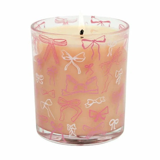 Candle in a glass jar with pink and white bow pattern on a white background