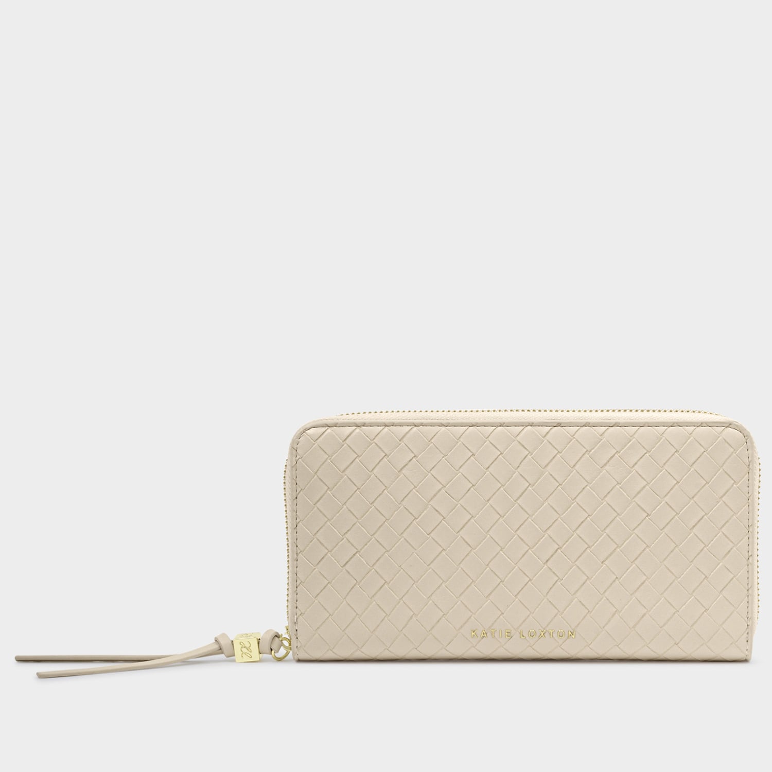 Vegan leather wallet by Katie Loxton showcased against a neutral studio backdrop featuring a cream basketweave texture, gold-toned logo lettering, and a matching tassel zipper pull with a signature logo charm