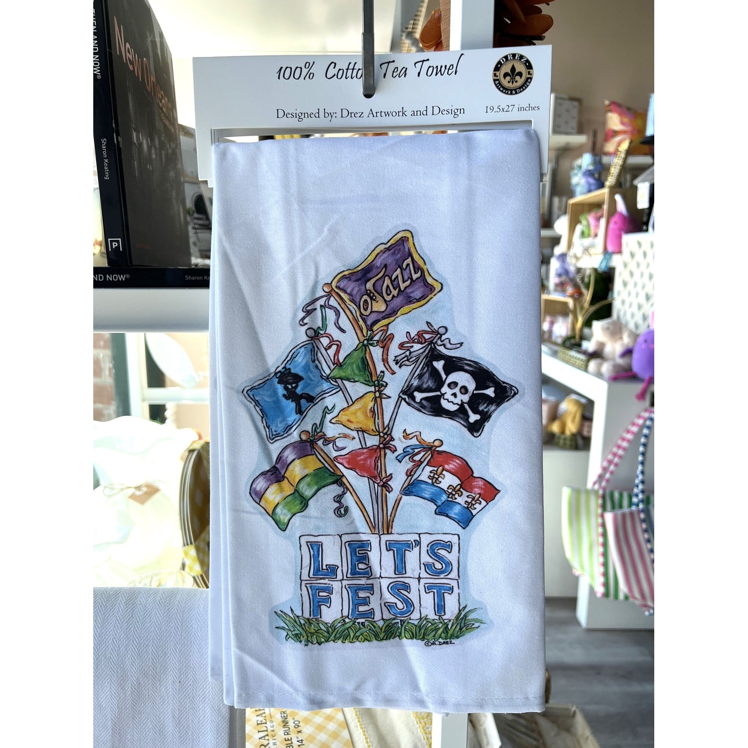 A white cotton tea towel with a colorful festival-themed design, including various flags and the text 'LET'S FEST' displayed.