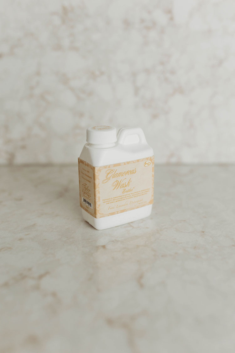 White bottle of Tyler Glamorous Wash fine laundry detergent on a marble surface