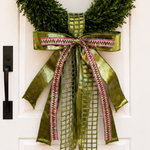 Bow of olive green velvet, green lattice and pink and green woven trim ribbons on a boxwood wreath