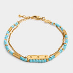 Gold chain bracelet with turquoise beads and a central bar charm featuring star engravings