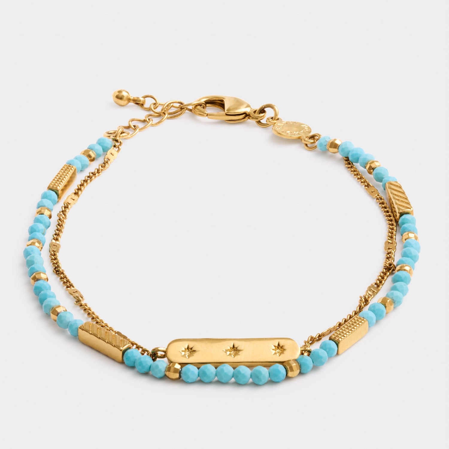 Gold chain bracelet with turquoise beads and a central bar charm featuring star engravings