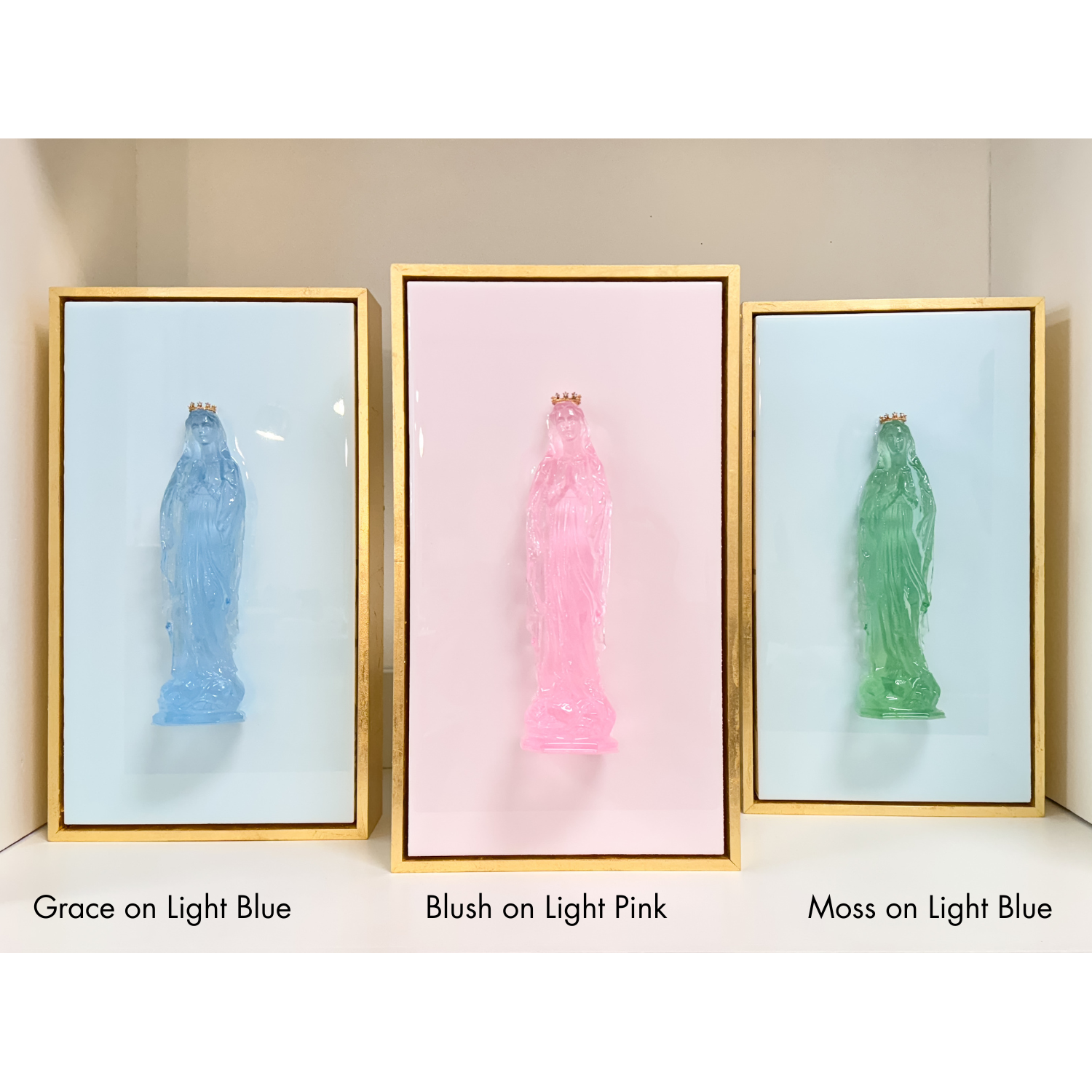 Three framed statues in different colors on a light background