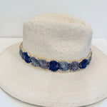 White straw hat with a blue floral band on a white background