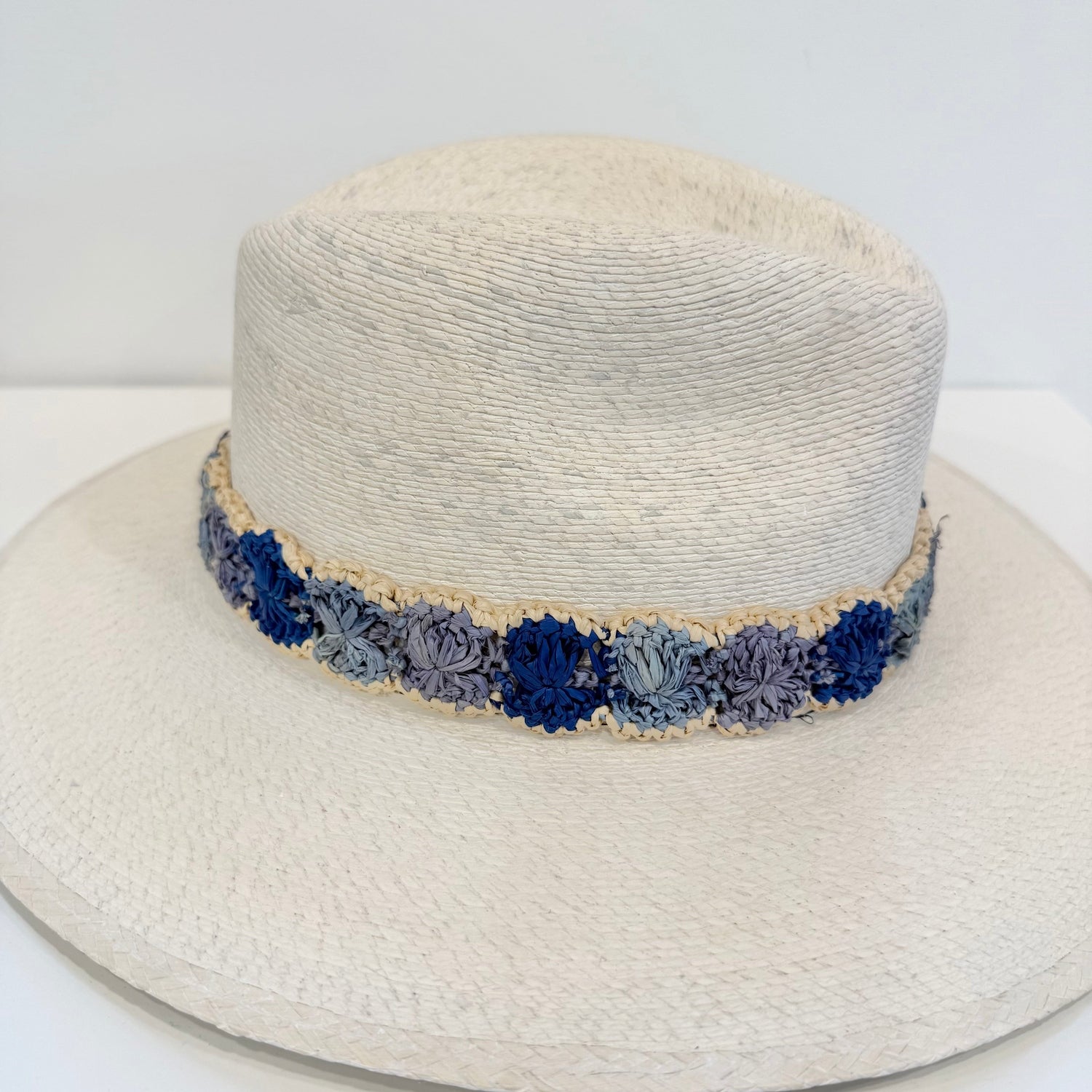 White straw hat with a blue floral band on a white background
