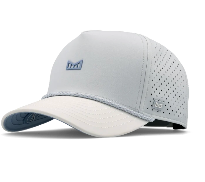 Product photograph by Melin of a high-performance baseball cap centered on a white background featuring a light grey perforated crown with a blue M logo, a cream-colored curved visor, and a matching braided rope accent