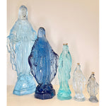 Set of five acrylic statues of a religious figure on a beige background