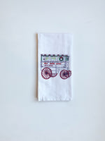 White towel printed with a candy cart decorated with a Christmas wreath, reading "NOLA Roman Candy"