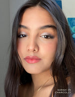 Close up portrait of a woman wearing charcoal eyeshadow and pink lipstick