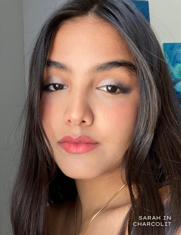 Close up portrait of a woman wearing charcoal eyeshadow and pink lipstick