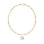 Gold beaded necklace with a single white pearl pendant