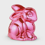 Sculpture of a metallic glossy bright pink stylized rabbit figurine in a squat position