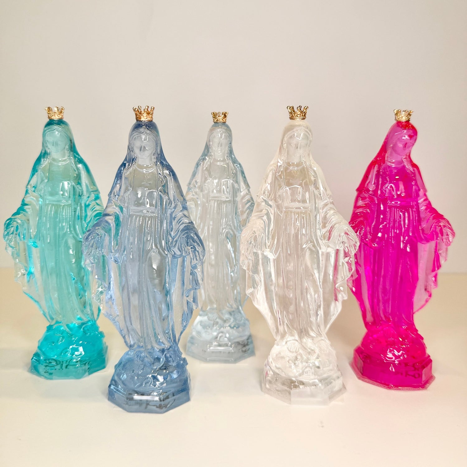 Five colorful statues of a religious figure with a white background