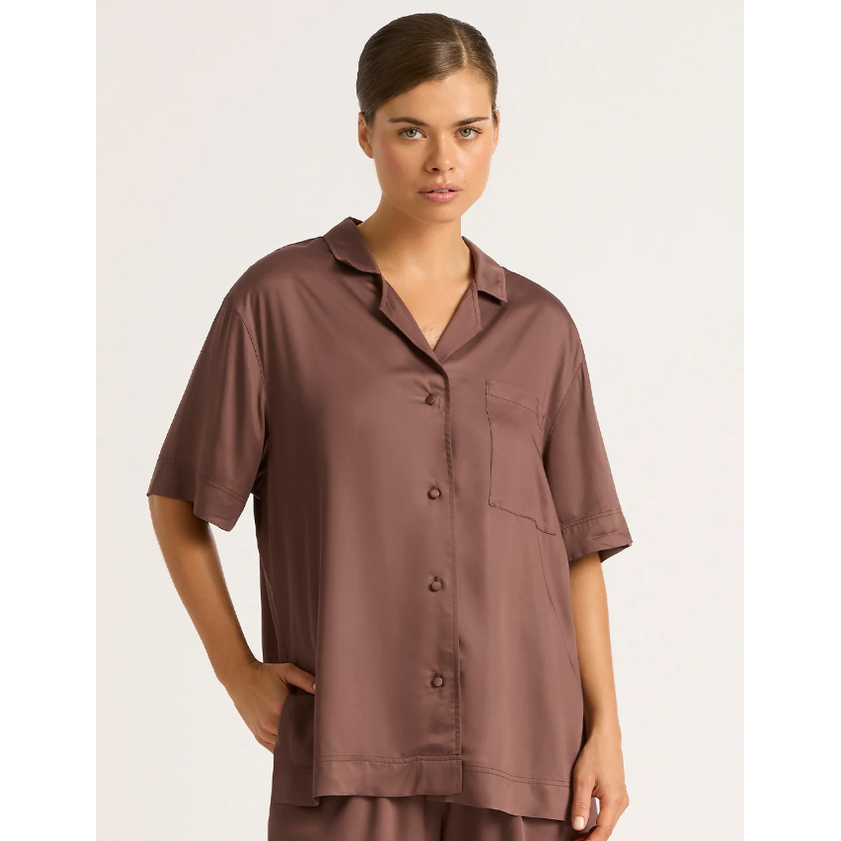A woman wearing a brown short-sleeve sleep shirt with a button-up front, styled in a relaxed, casual manner.