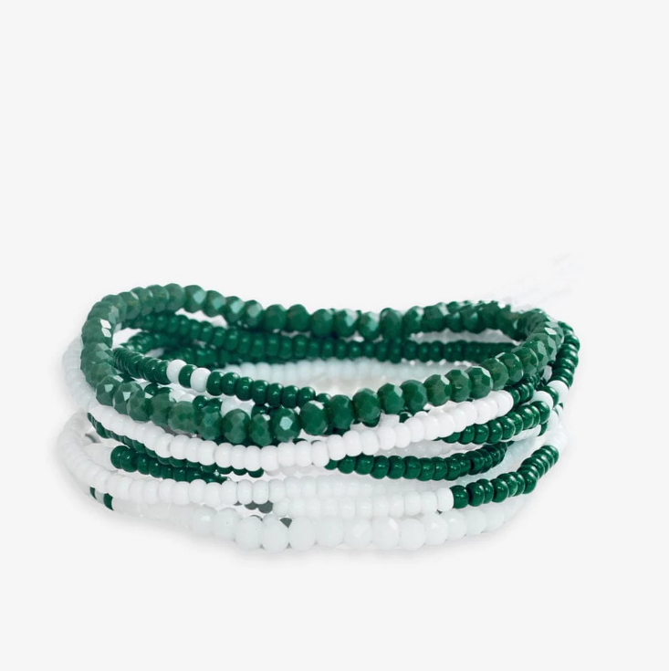 Photography of a stack of mixed green and white beaded bracelets featuring shiny faceted emerald beads, tiny white seed beads, and smooth matte white beads artfully layered