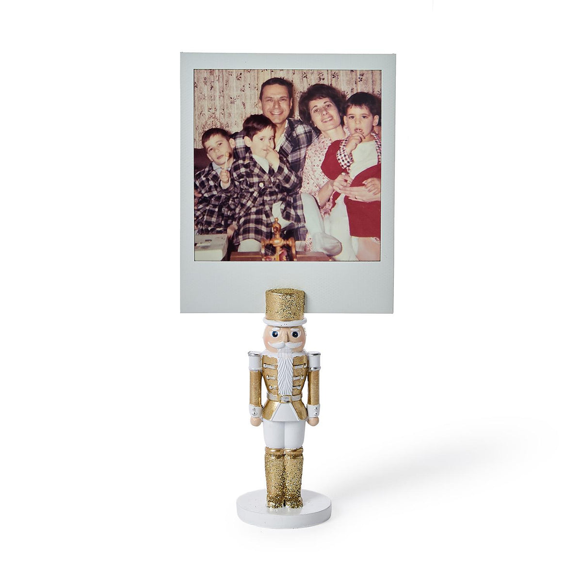 White and gold nutcracker place card holder holding a vintage instant photo of a family
