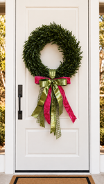 White front door with a boxwood wreath and an olive green and hot pink ribbon bow