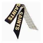 Silk twilly scarf featuring the New Orleans Saints brand in bold gold block lettering and a repeating fleur-de-lis pattern on the white reverse side with pointed ends