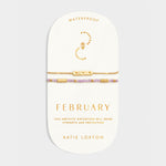 Two gold tone bracelets with purple amethyst beads on a February birthstone collection display card
