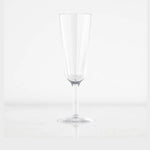 Photograph of a single clear empty champagne flute featuring a tall slender bowl and delicate stem resting on a reflective white surface