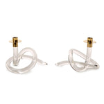 Clear glass and brass modern candlesticks featuring sculptural knot bases with gold candle holders