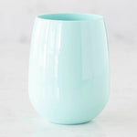 Photograph of an aqua blue glossy stemless tumbler on a white marble surface showcasing subtle reflections