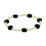 A stretch bracelet featuring alternating polished gold beads and faceted black onyx pillow-shaped stones on a white background