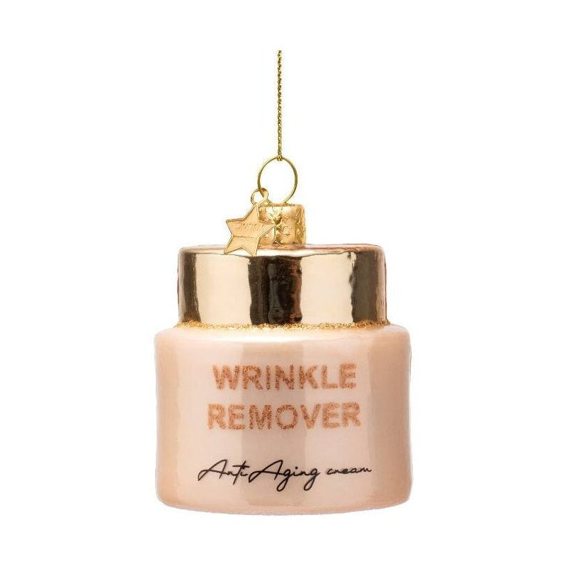 Glass ornament shaped like a light peachy-pink jar of "WRINKLE REMOVER Anti-Aging cream" with gold glitter accents, a shiny gold top, and a small gold star charm