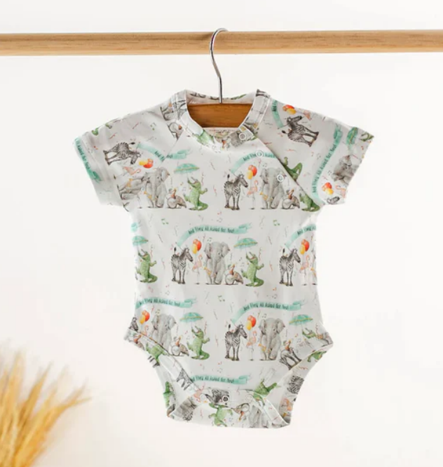 White baby bodysuit with a repeating pattern of cartoon animals including elephants zebras and crocodiles