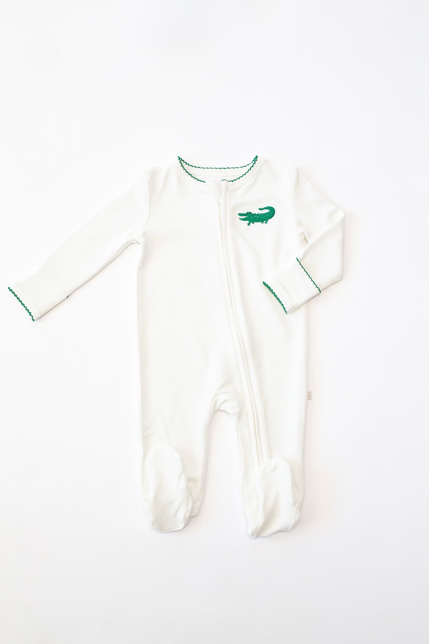 White long sleeve baby footie with green alligator embroidery and green scalloped trim