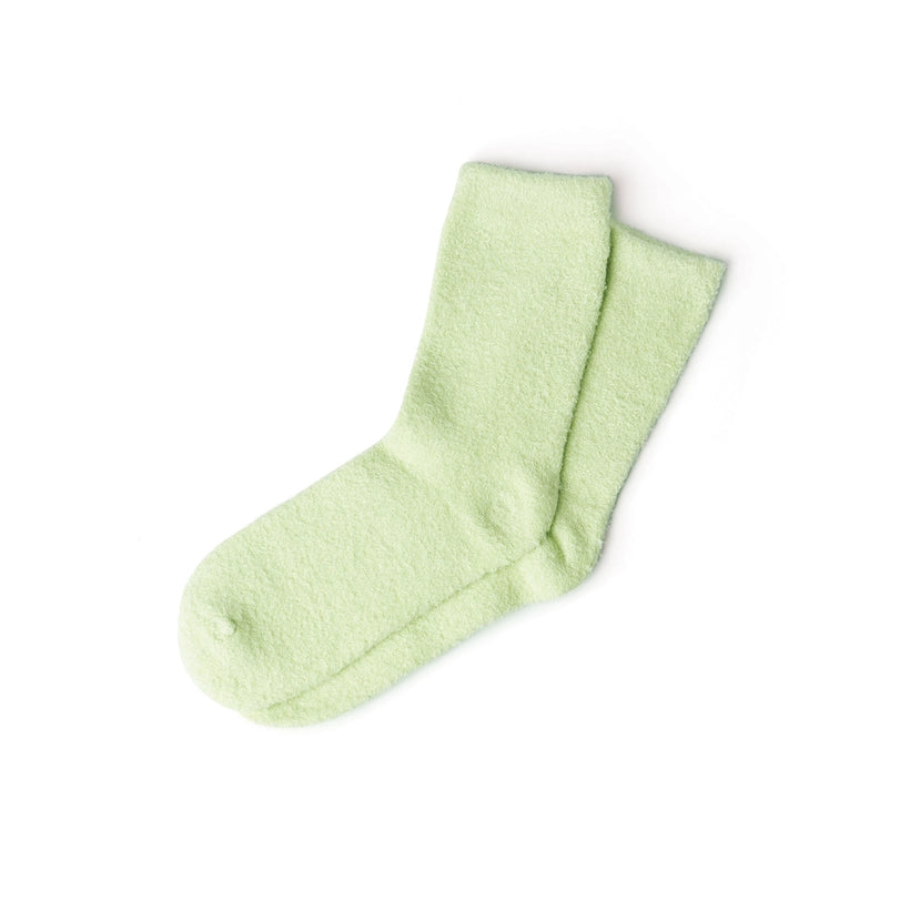 Pair of light green fuzzy crew socks on a white background