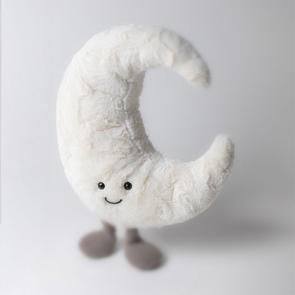 Plush crescent moon toy with a smiling face and small grey feet